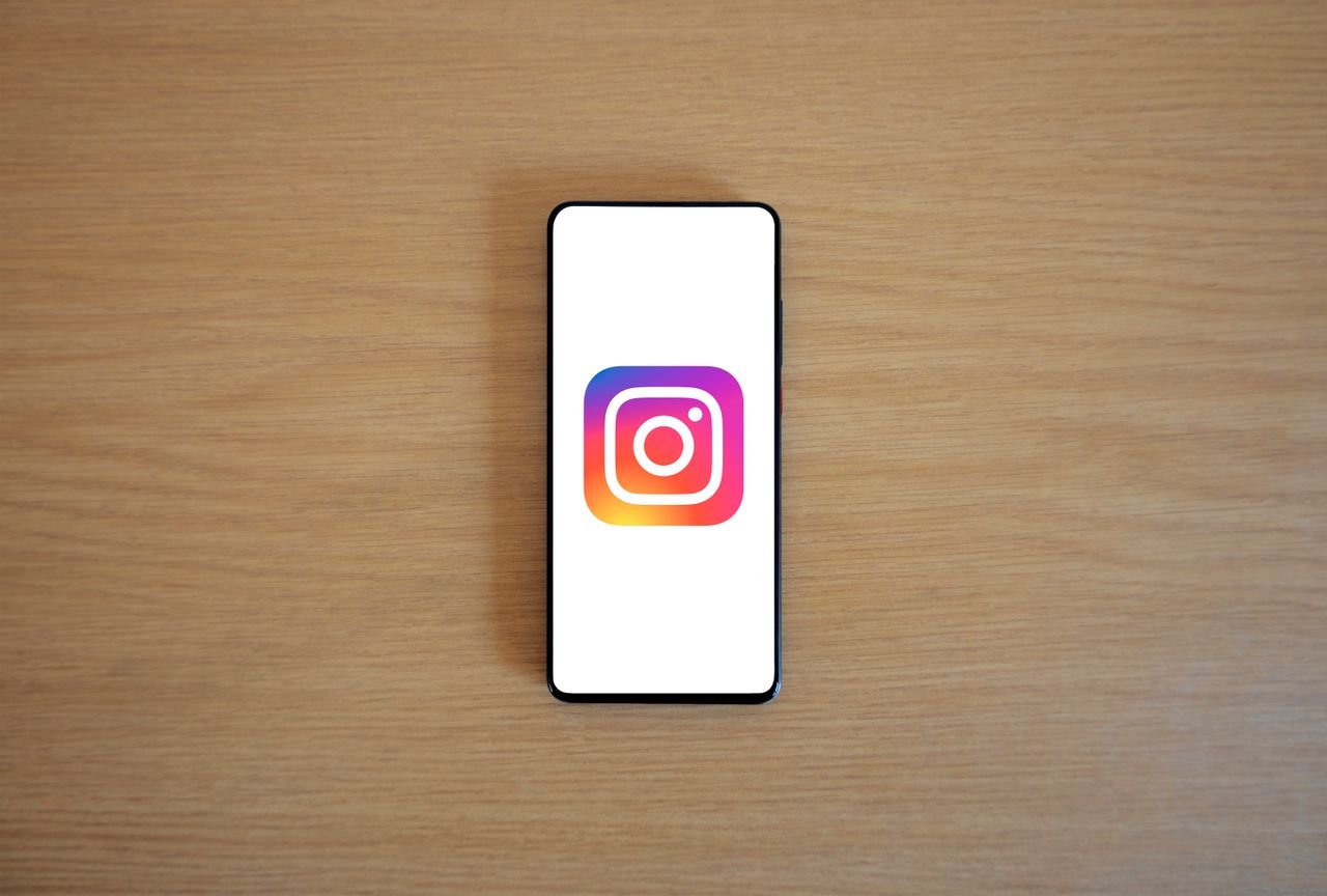 A smartphone with the Instagram logo on display, placed on a wooden surface. Perfect for technology and social media themes.