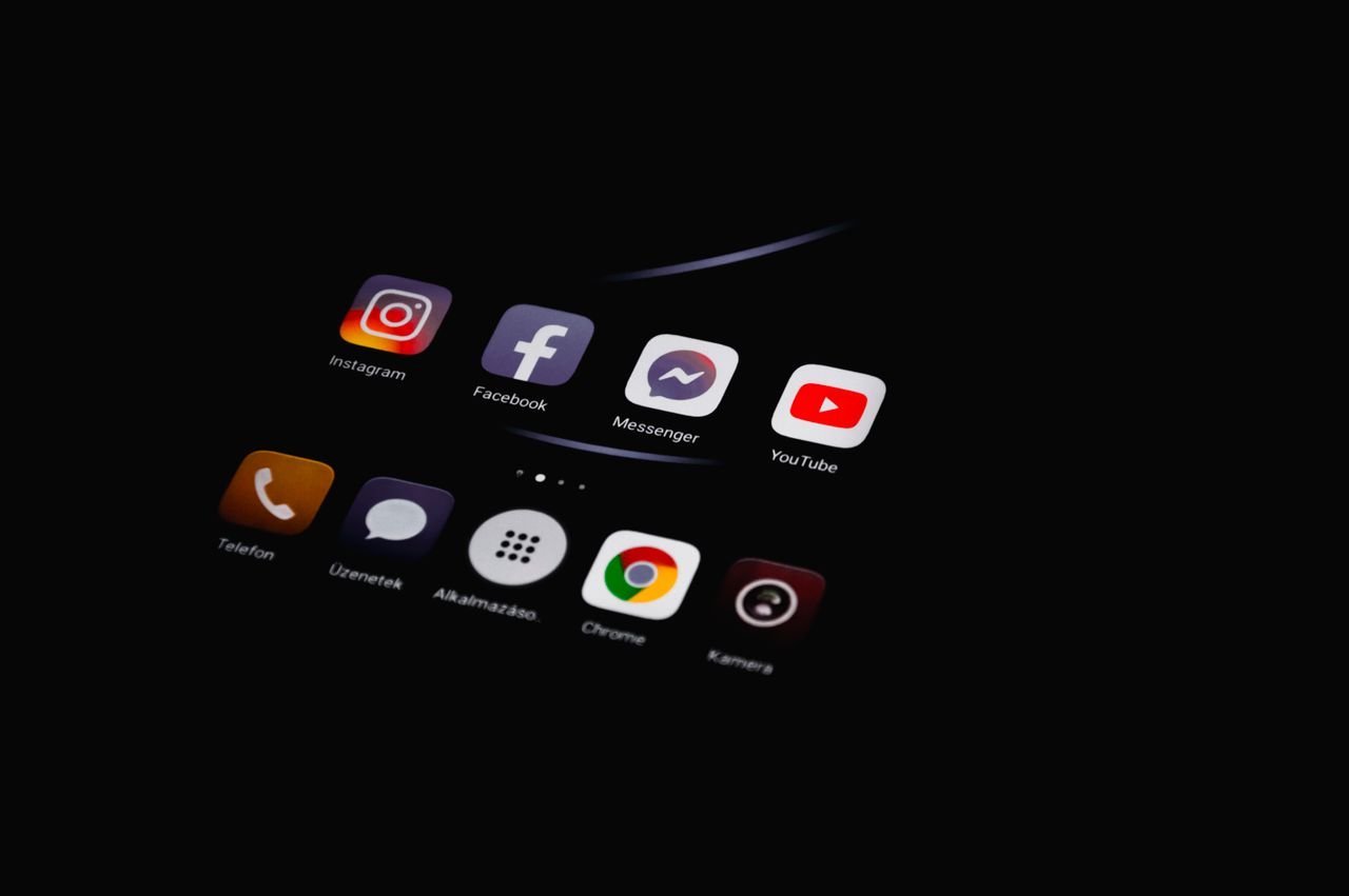 Home Close-up of smartphone displaying popular social media apps in dim lighting.