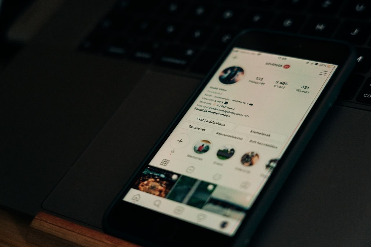 Home Close-up of smartphone showing a social media profile screen next to a laptop.